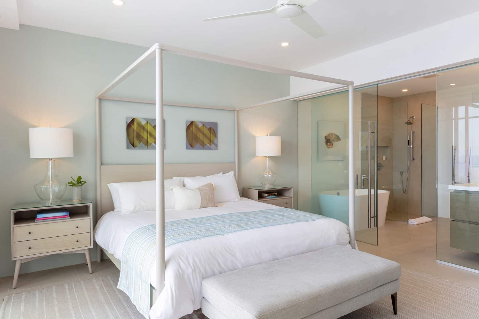 A bedroom with a canopy bed and glass shower is perfect for a cozy retreat in Bermuda.