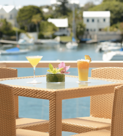 A wicker table with a drink on it, nestled in a Bermuda vacation rental.
