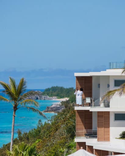 A man is sitting on a balcony overlooking the ocean in Bermuda.