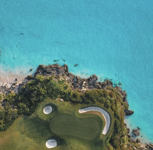 An aerial view of a golf course by the ocean.