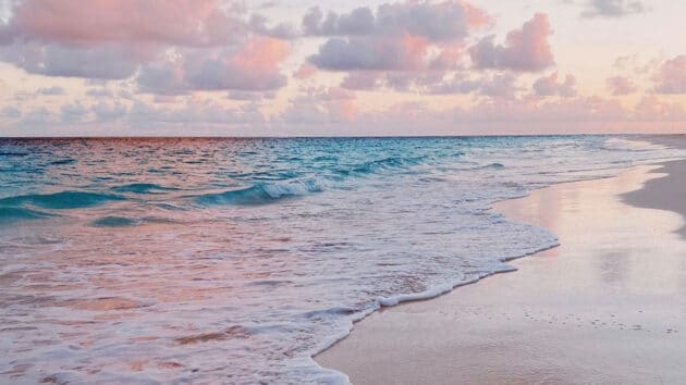 A beach with pink water and clouds at sunset, perfect for a Bermuda vacation getaway.
