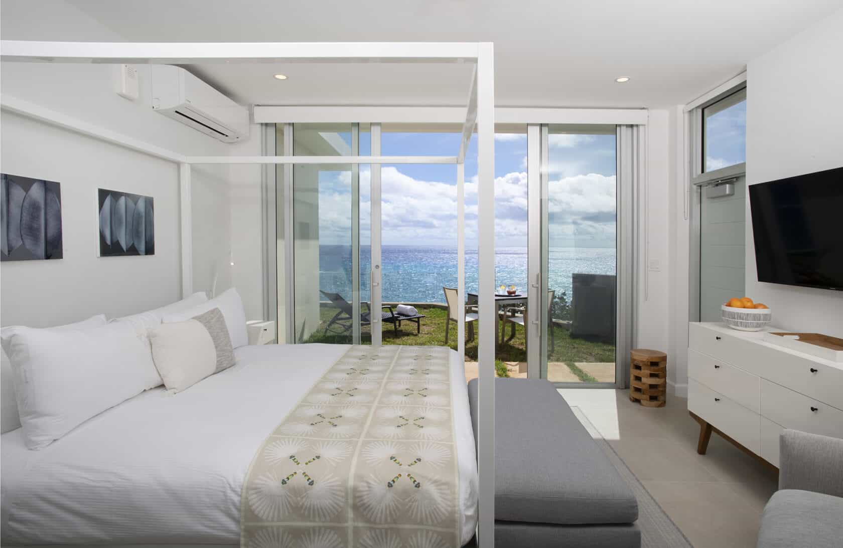 A white bedroom with a view of the ocean, perfect for a bermuda vacation rental.