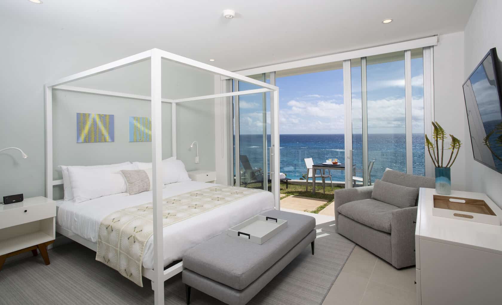 A bedroom with a four poster bed and an ocean view. Located in Bermuda residences.